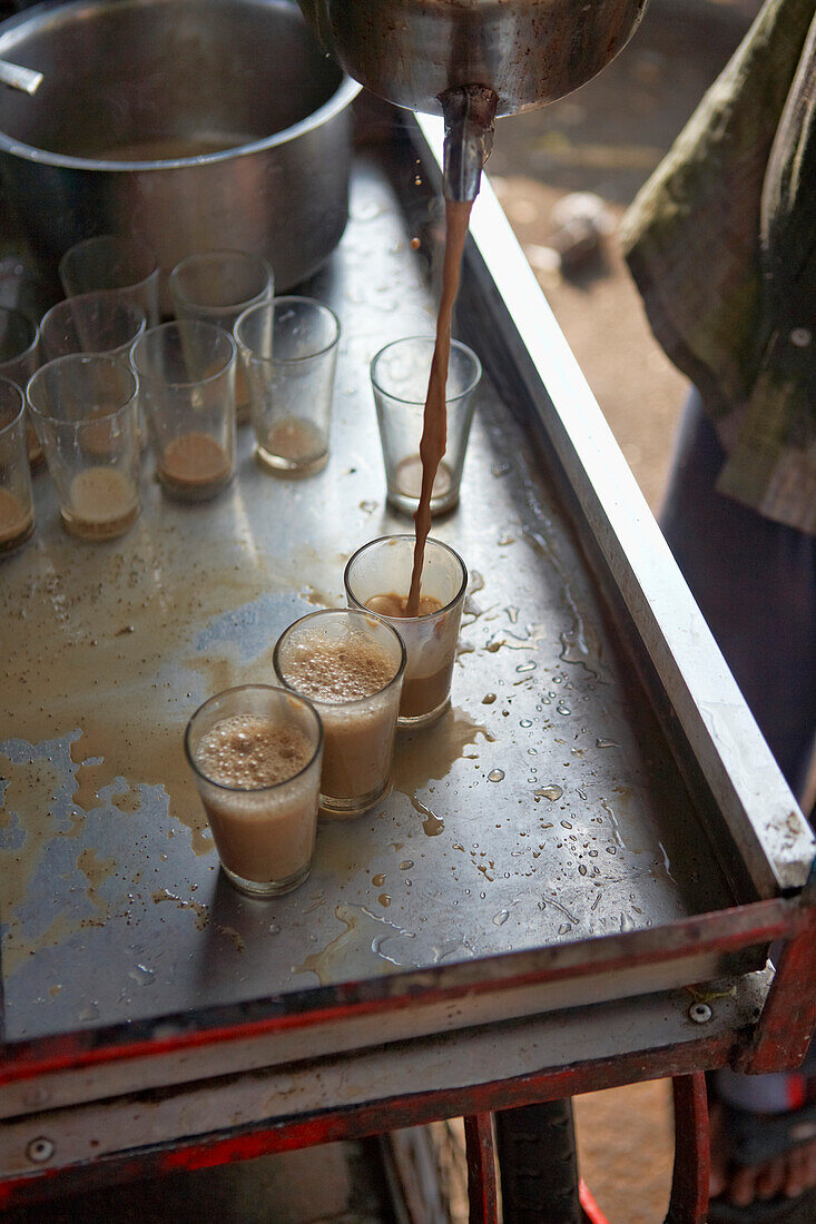 Ein Chai Wallah schenkt Gläser mit Masala Chai ein, Mysore, Karnataka, Indien