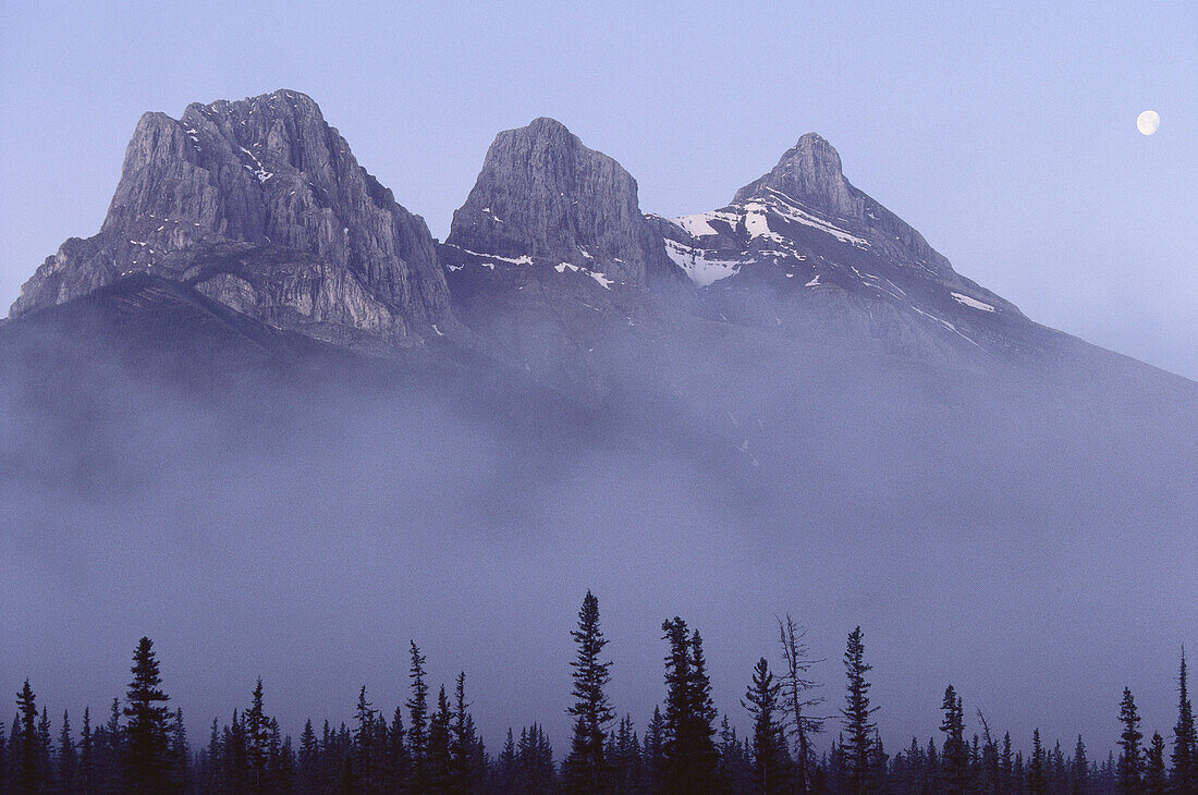 Monduntergang über Three Sisters, östlich von Canmore, Alberta, Kanada