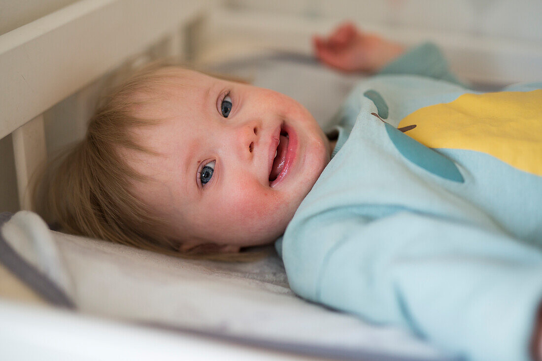 Lächelndes Baby mit Down-Syndrom schaut in die Kamera