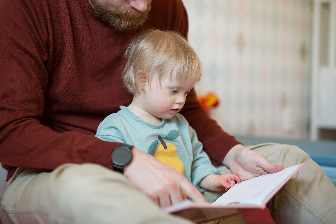 Father reading book to child with down syndrome