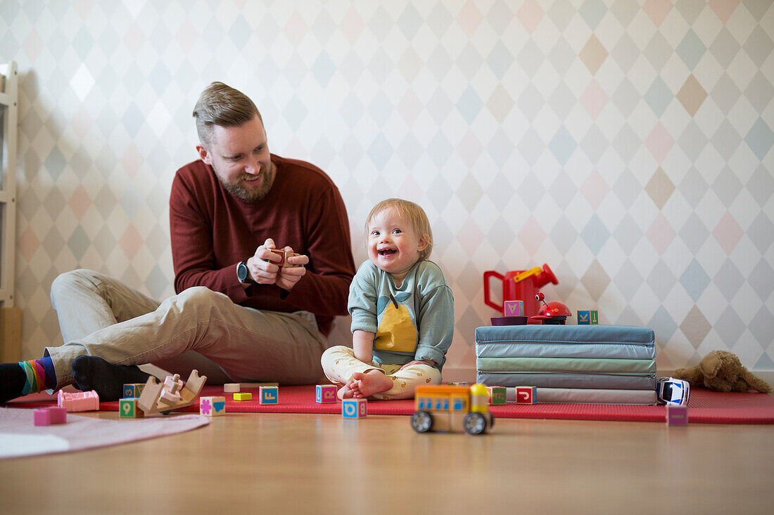 Father playing with baby with down syndrome