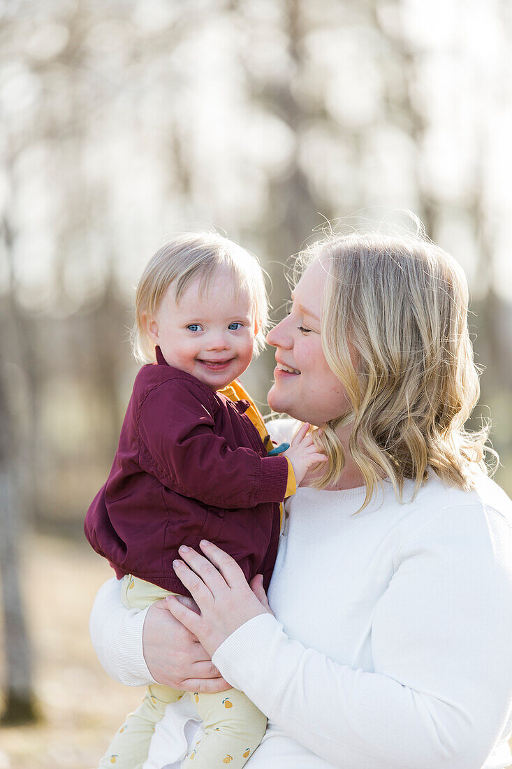 Mother holding smiling baby with down syndrome