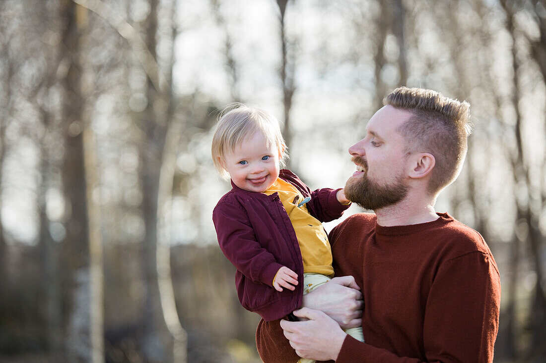 Vater hält lächelndes Baby mit Down-Syndrom