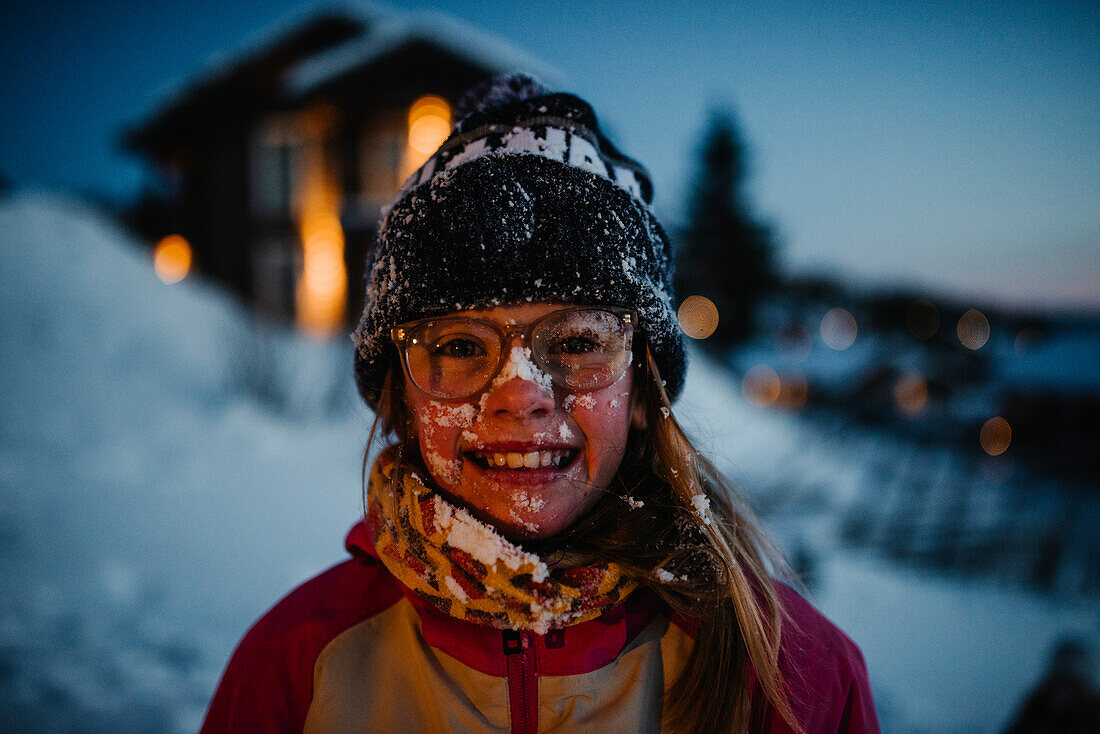 Glückliches Mädchen im Schnee, das in die Kamera schaut