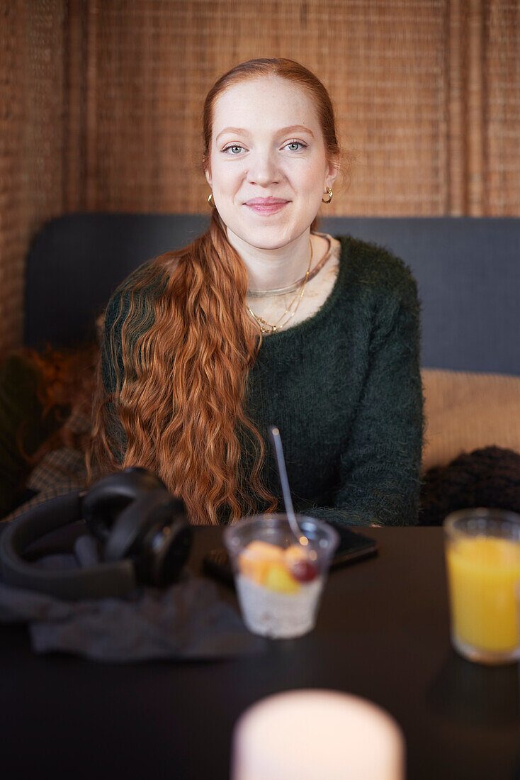 Porträt einer lächelnden jungen rothaarigen Frau in einem Cafe