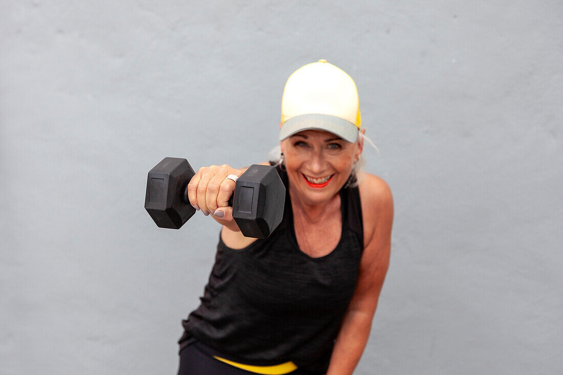 Portrait of fit senior woman with cool haircut holding dumbbells