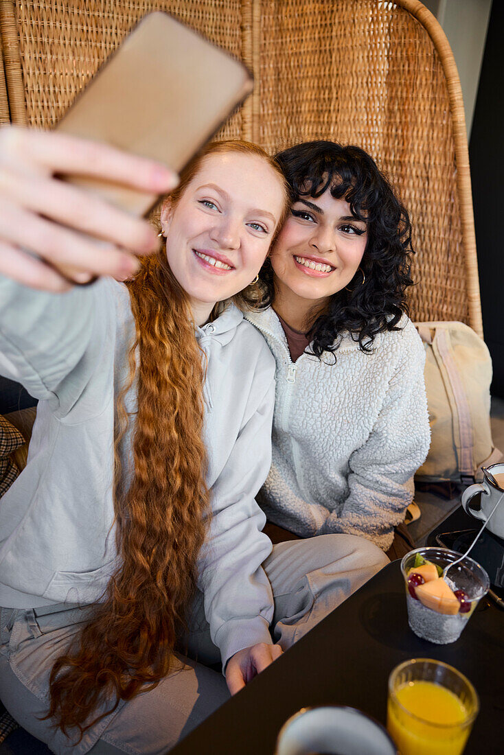 Smiling young women taking selfie in cafe