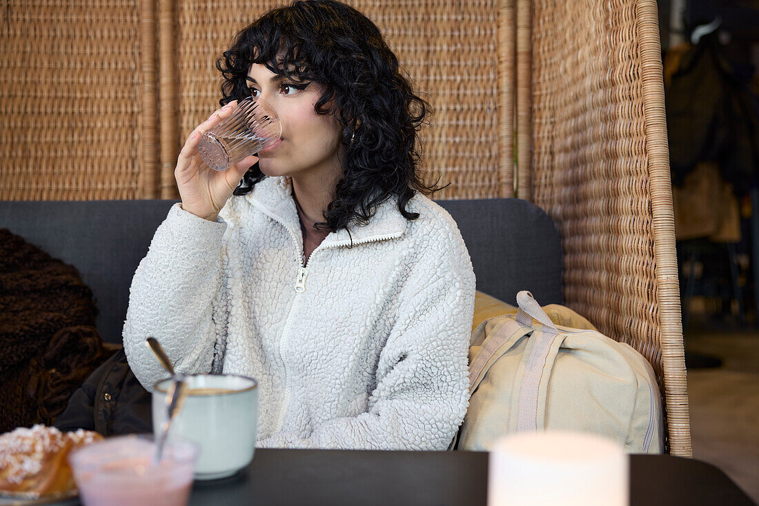 Young woman drinking water in cafe