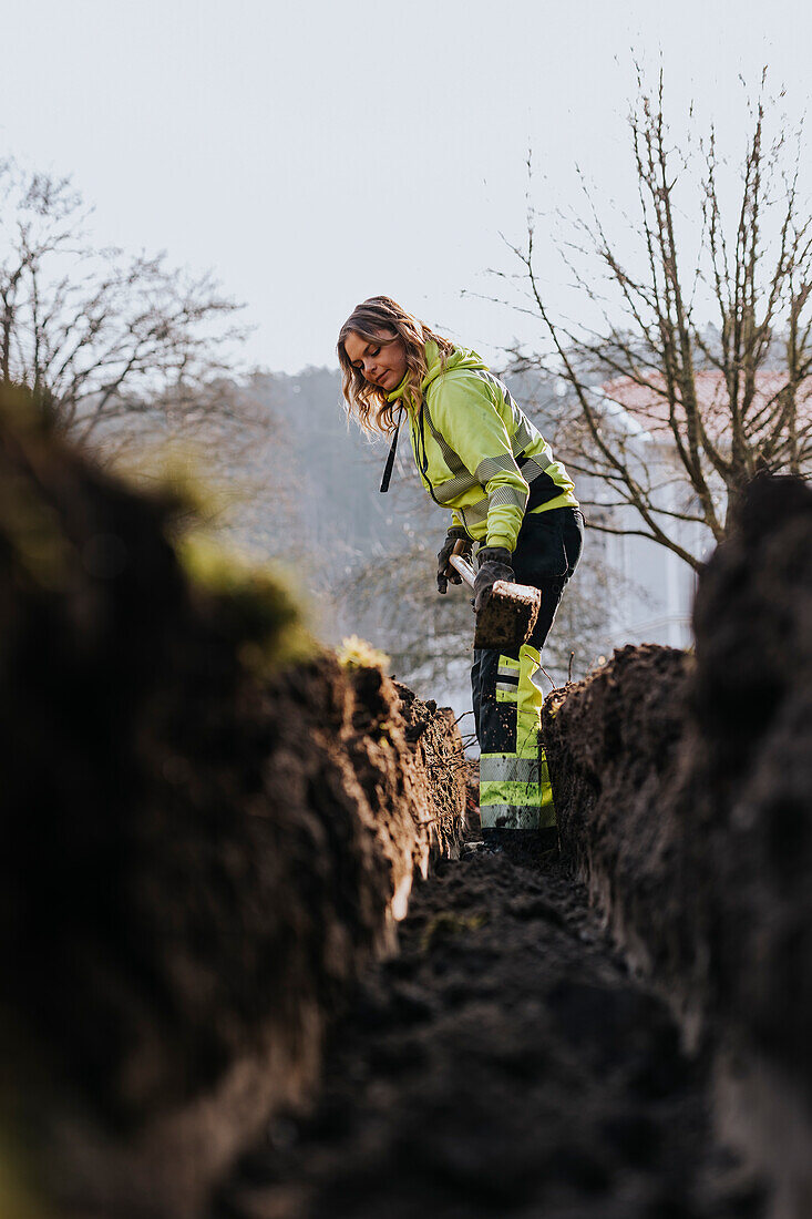 Junge Arbeiterin gräbt einen Graben