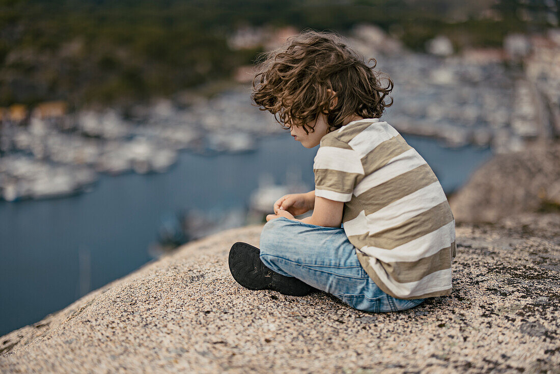 Junge sitzt und schaut aufs Meer