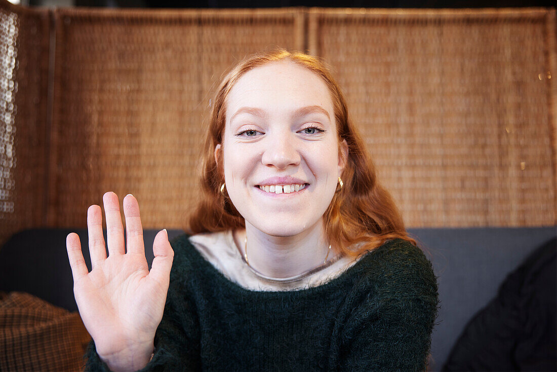 Portrait of smiling woman looking and waiving at camera