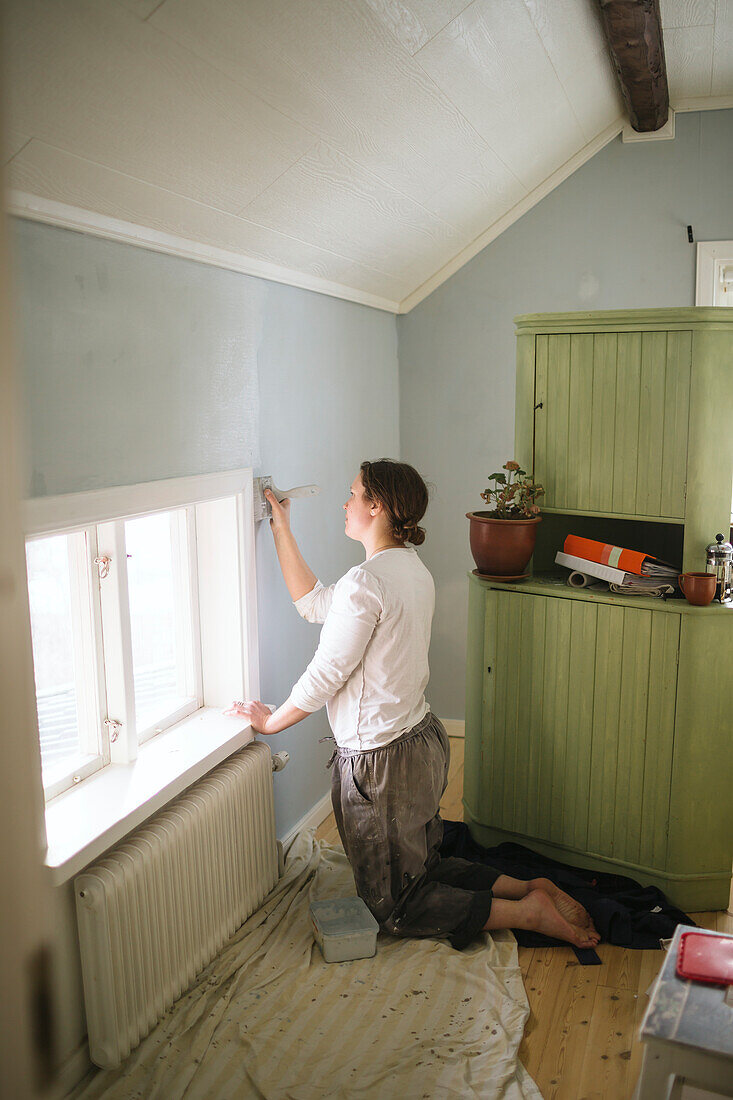 Woman painting wall at home