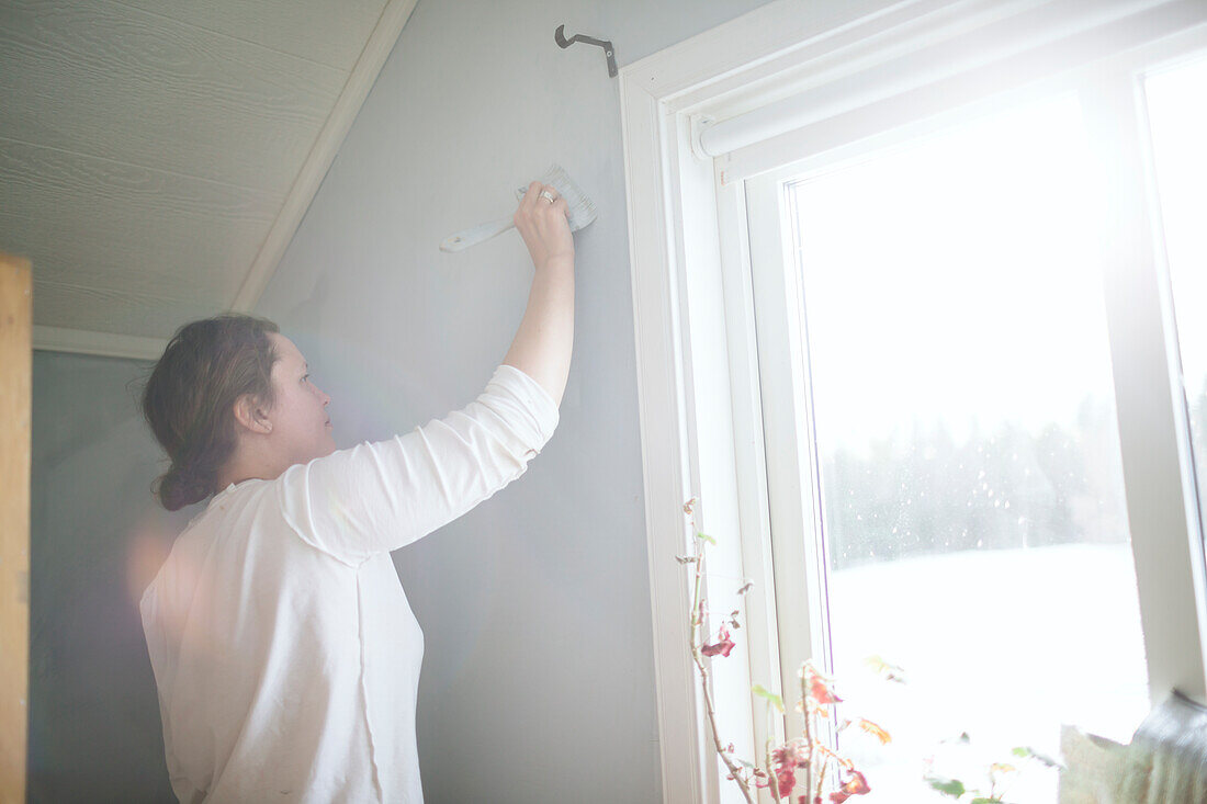 Frau streicht Wand zu Hause