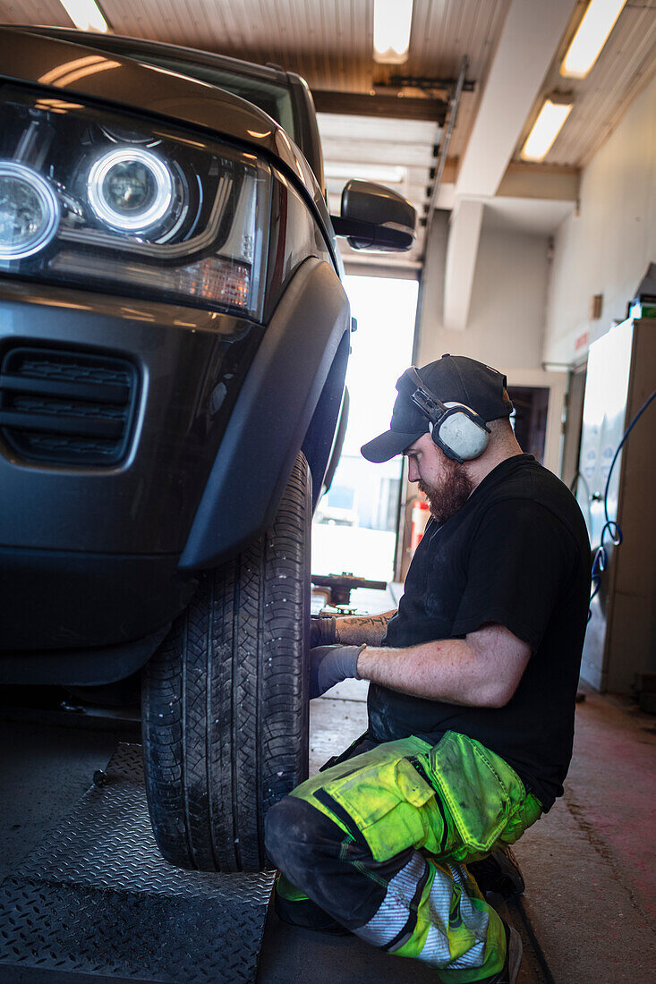 Mechaniker in der Werkstatt wechselt Reifen am Auto