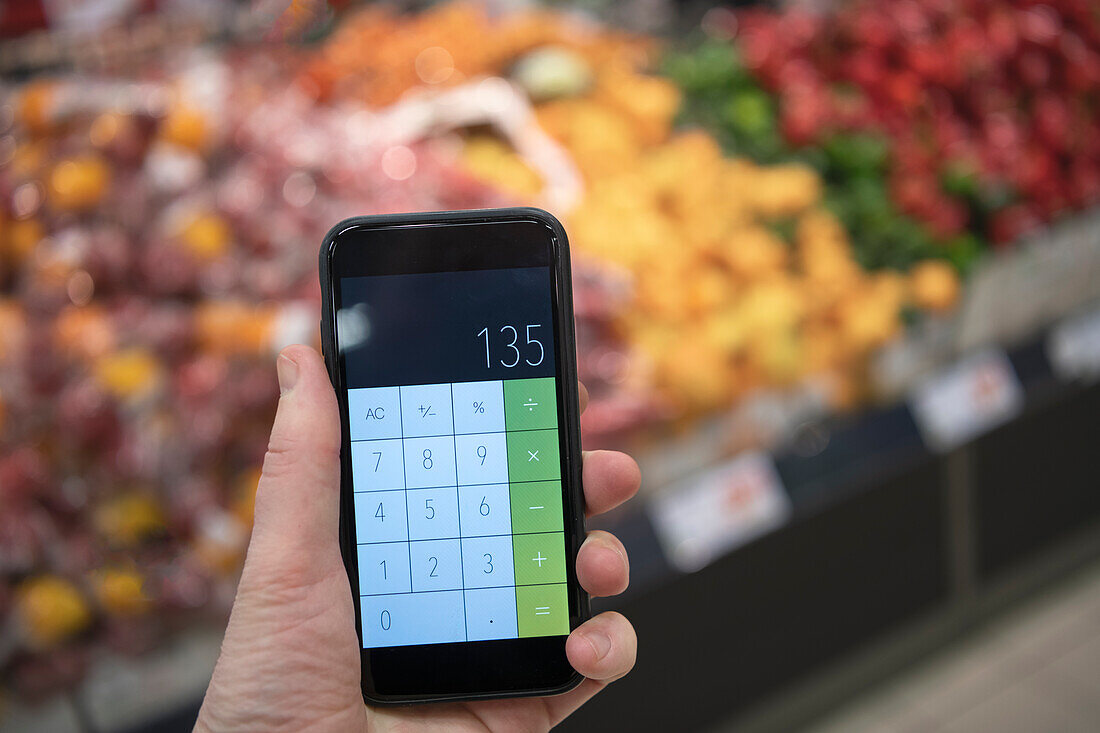 Hand hält Taschenrechner im Supermarkt