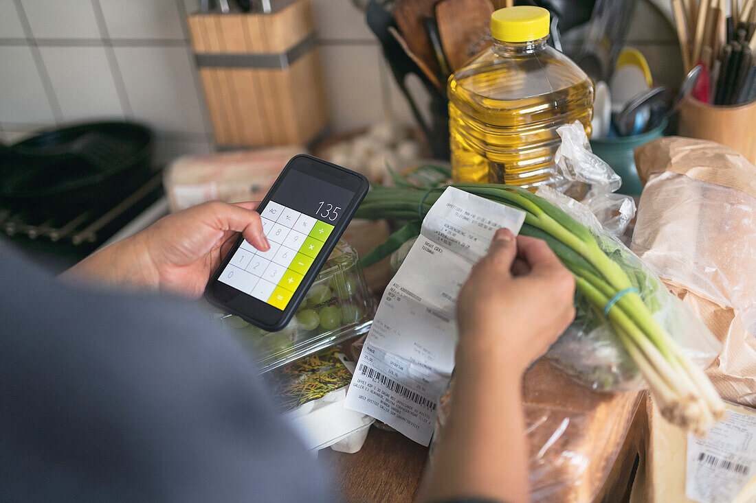 Person prüft Kassenzettel im Supermarkt während der Inflation mit Preisanstieg bei Lebensmitteln und Konsumgütern