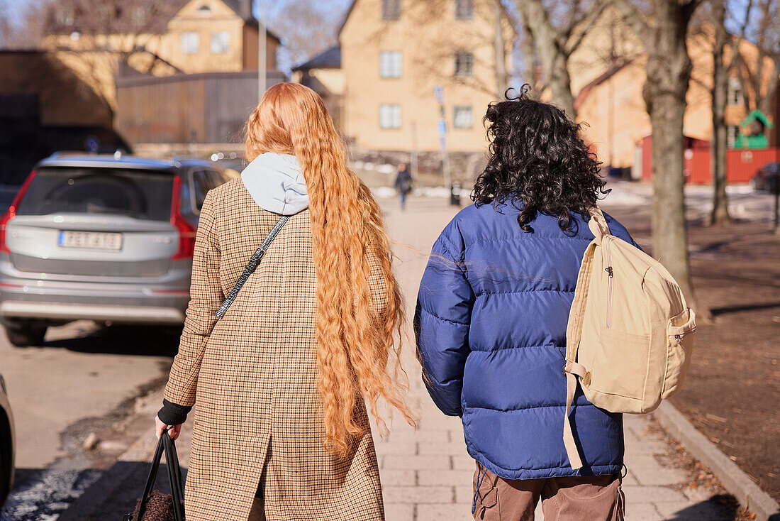 Freundinnen gehen zusammen im Freien auf einem Gehweg in der Stadt