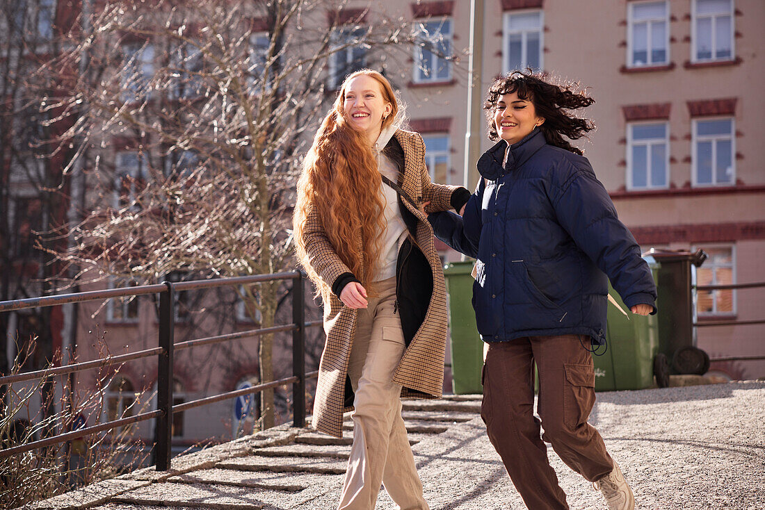 Freundinnen gehen zusammen im Freien auf einem Gehweg in der Stadt