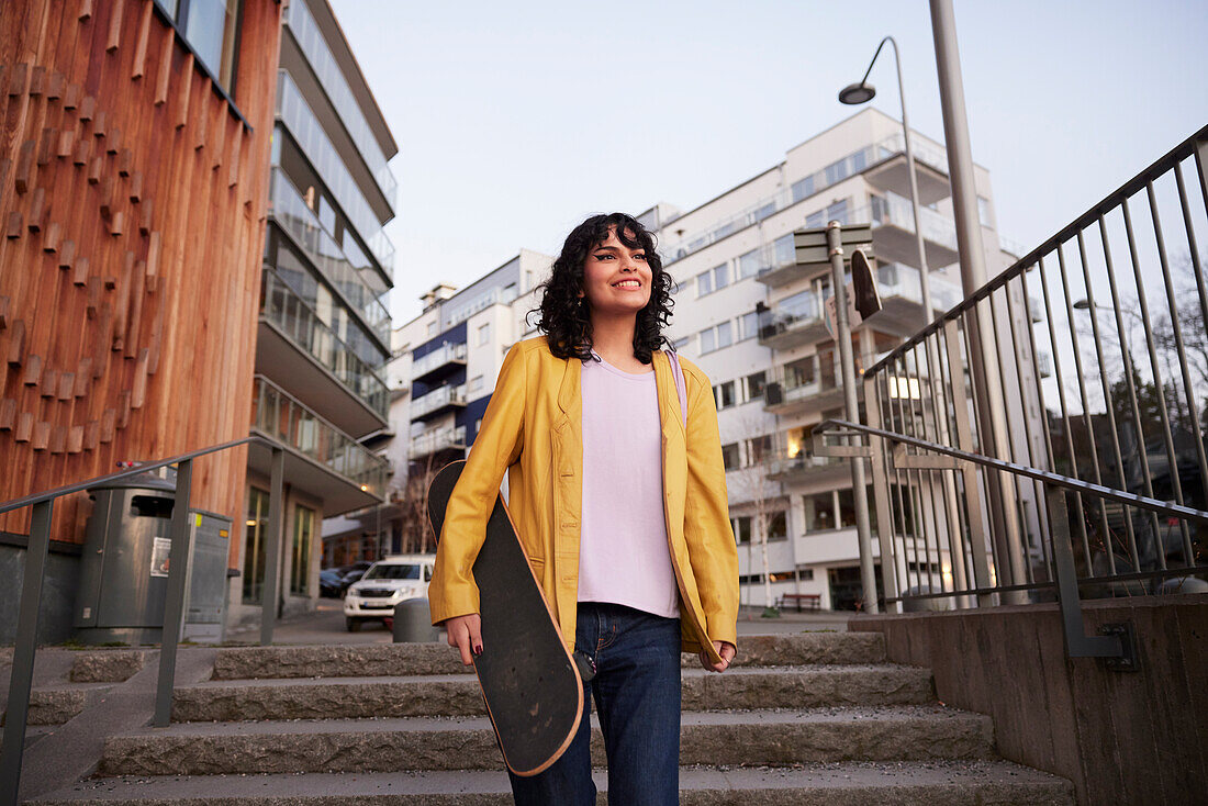 Low angle view of woman walking down stairs and carrying skateboard