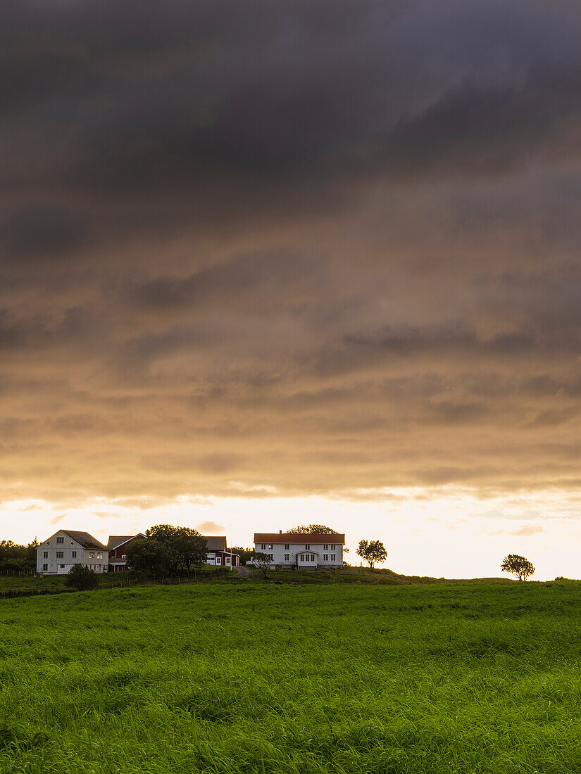 Dramatische Gewitterwolken über einer Wiese mit Häusern am Horizont