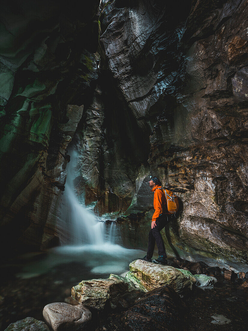 Man looking at waterfall while exploring cave