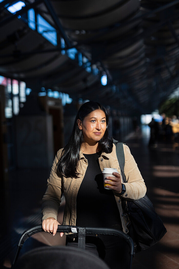 Blick auf Frau mit Einwegbecher am Bahnhof