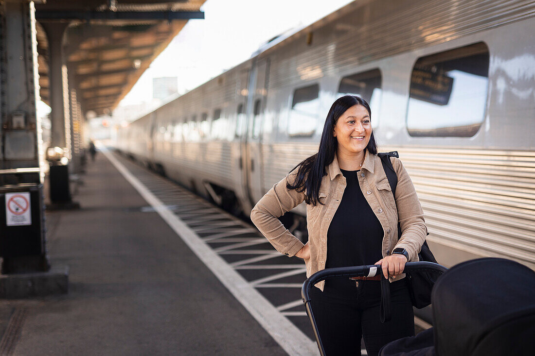 Mid adult woman at train station pushing pram