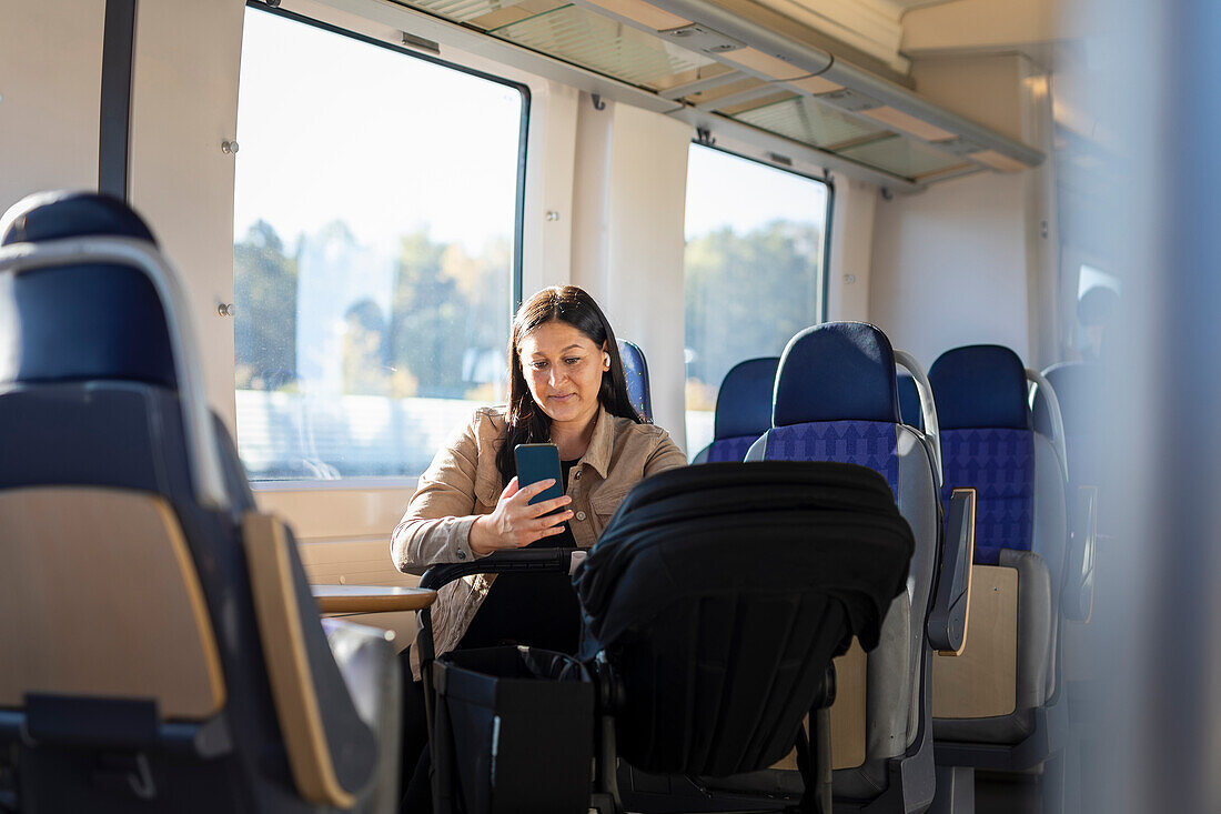 Mid adult woman in train using cell phone