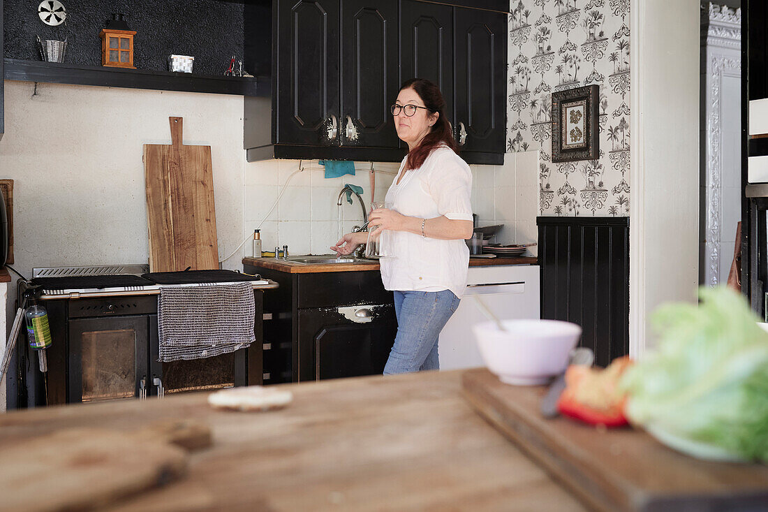 Mature woman standing in kitchen and looking away