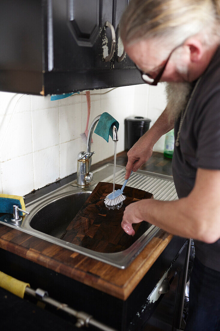 Mann in der Küche beim Geschirrspülen am Spülbecken