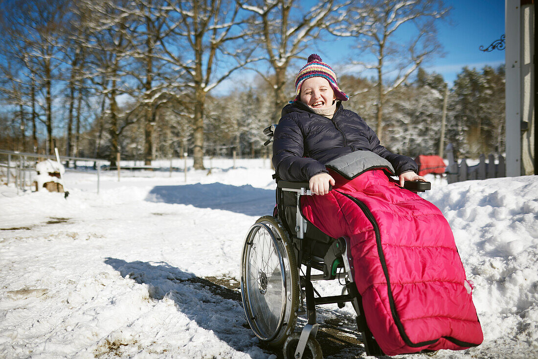 Behindertes Teenager-Mädchen sitzt im Rollstuhl an einem sonnigen Wintertag