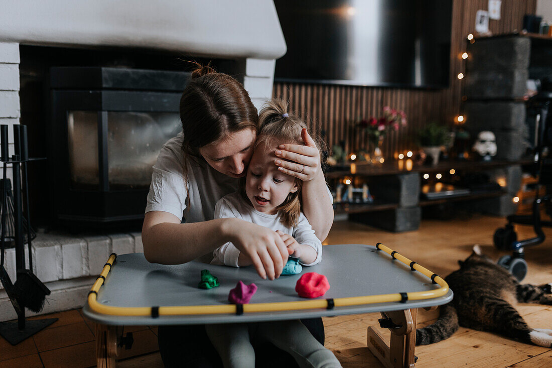 Mutter mit behindertem Kind spielt mit Spielknete