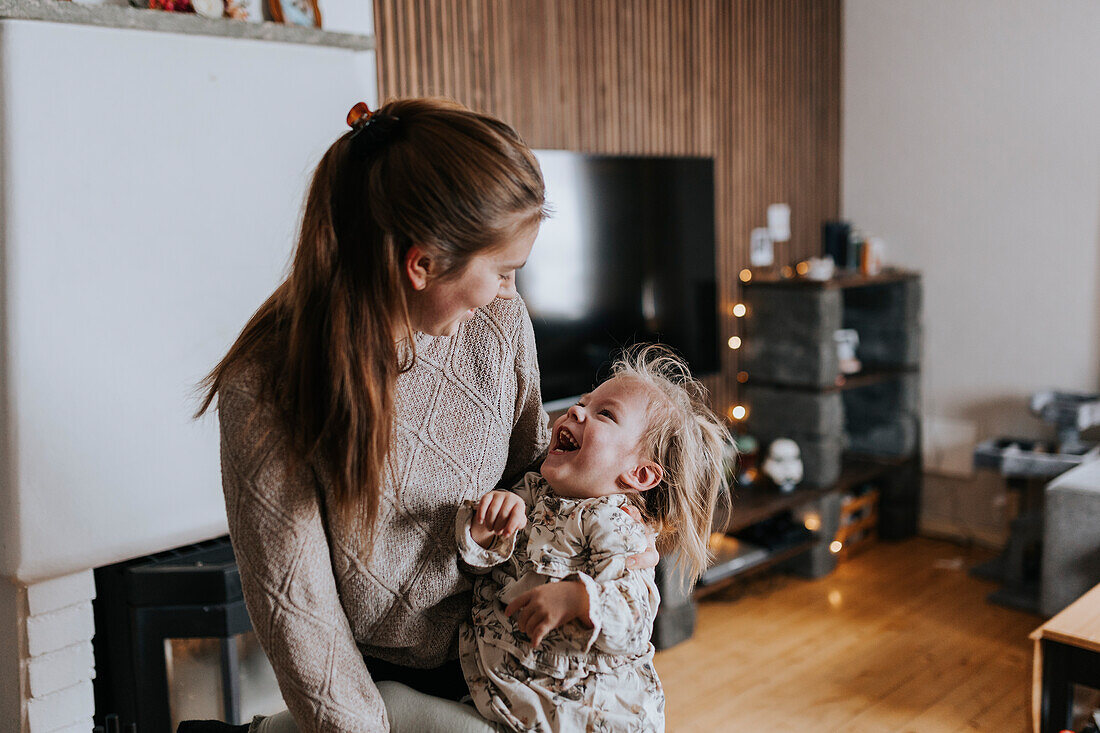 Lächelnde Mutter sitzt mit behindertem Kind im Wohnzimmer