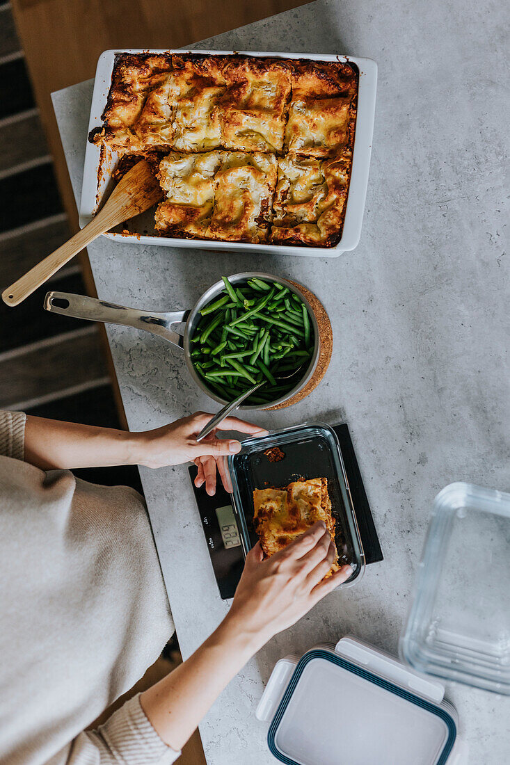 Woman weighing lasagna portions as part of meal prep