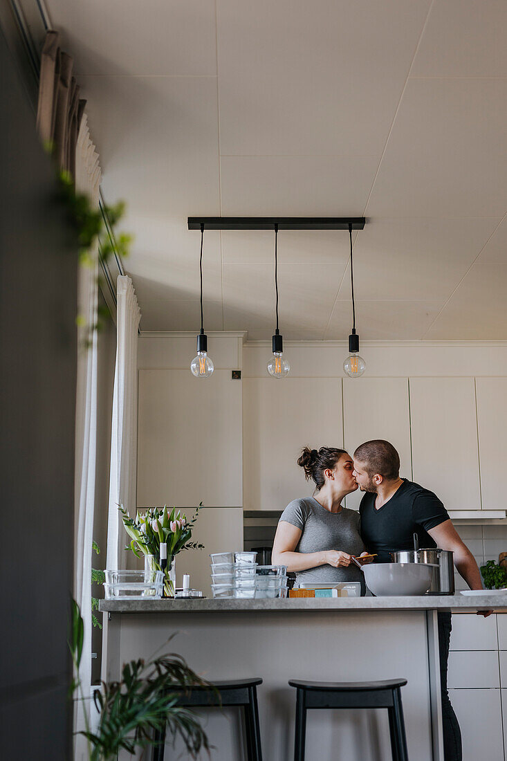 Couple kissing while doing healthy meal prep at home