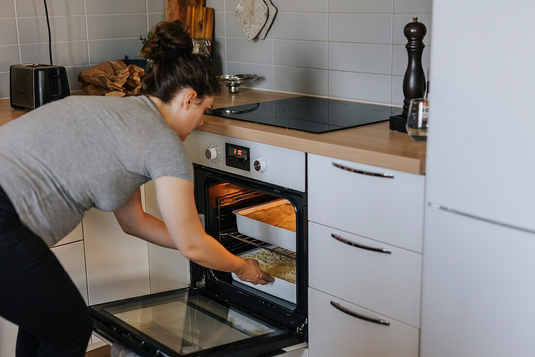 Pregnant woman putting dish in oven