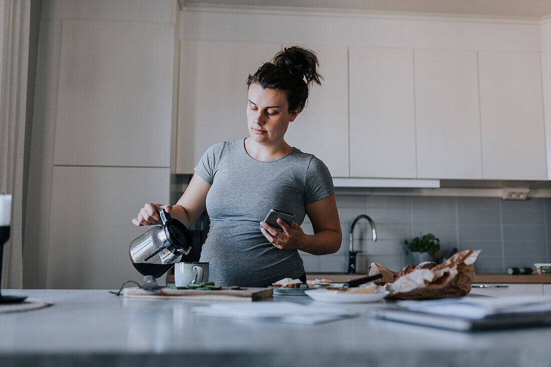 Pregnant woman pouring coffee for breakfast