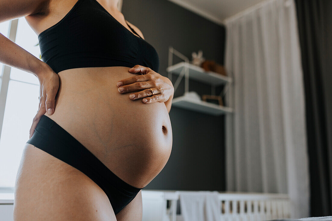 Nahaufnahme einer schwangeren Frau, die ihren Bauch berührt