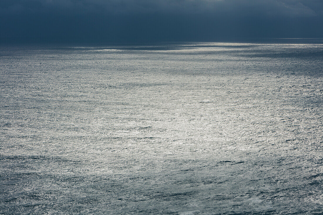 Sturmwolken über dem Pazifischen Ozean in der Abenddämmerung, Spiegelungen auf der Wasseroberfläche.