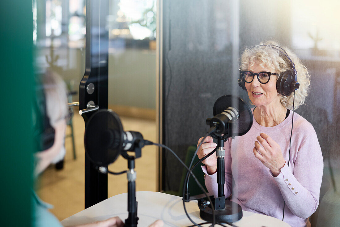 Ältere Frau sitzt und moderiert Podcast oder Radiosendung oder Podcast