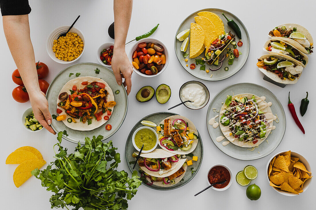 Person preparing healthy feast with various Mexican food