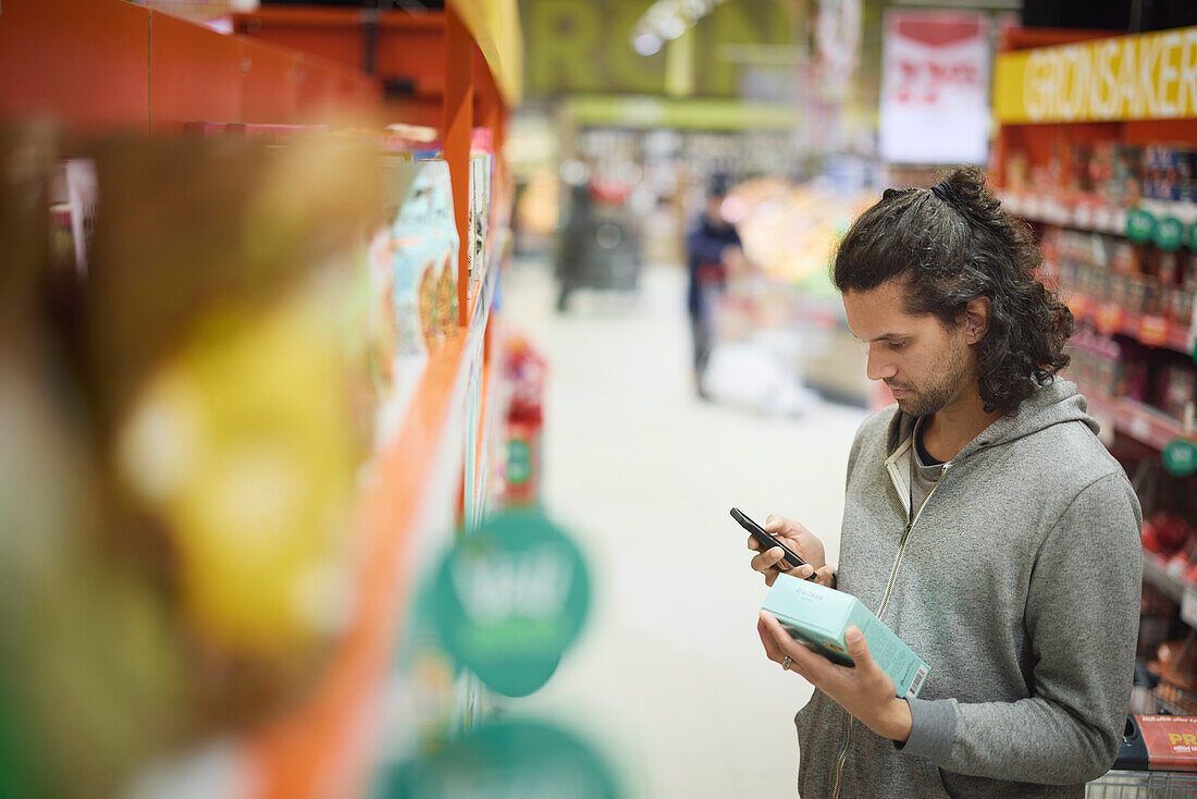 Mann im Supermarkt benutzt Handy