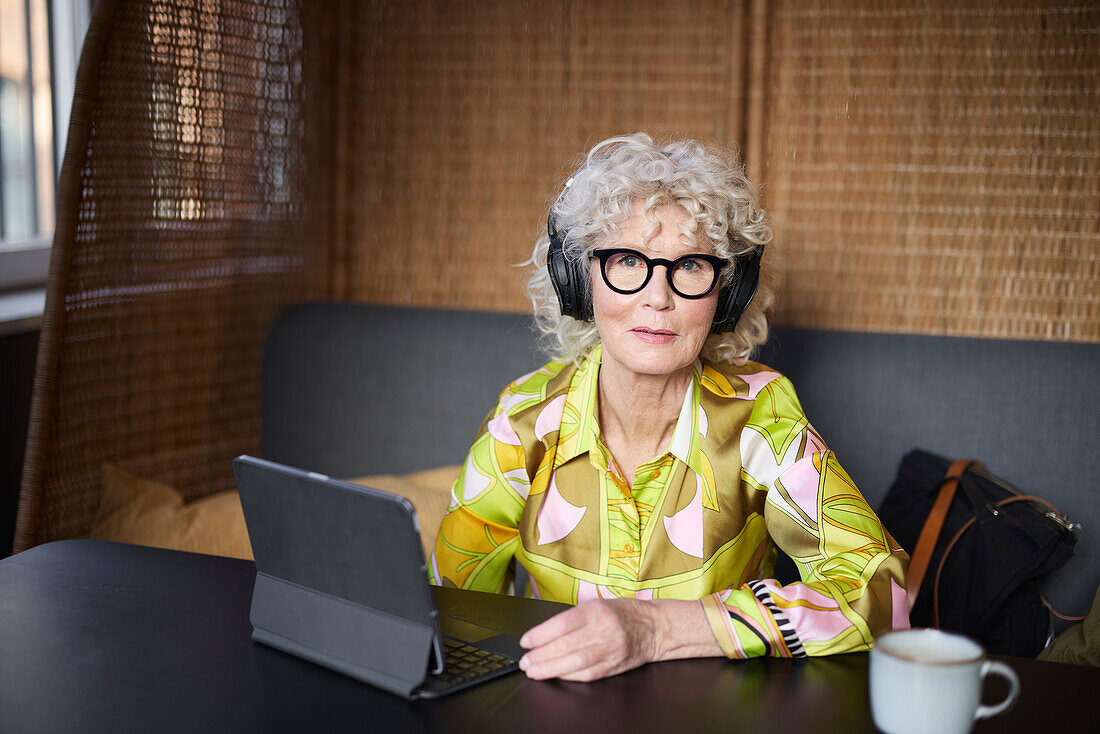 Portrait of senior woman with headphones using tablet