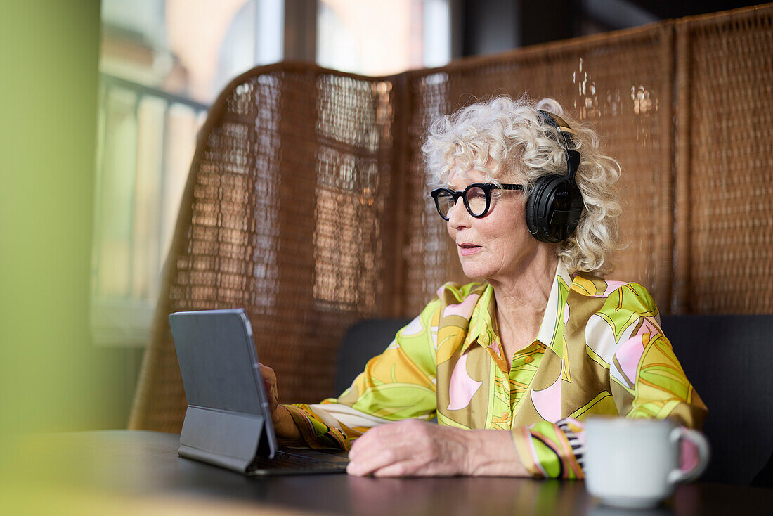 Senior woman in headphones using tablet