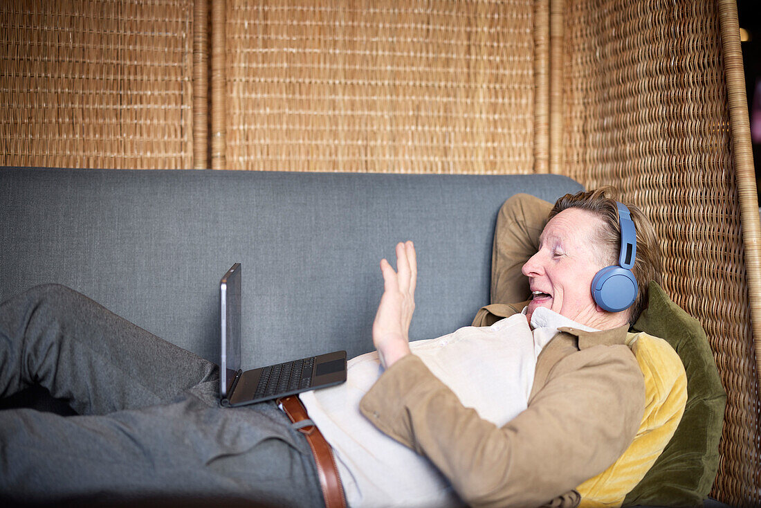 Älterer Mann mit Kopfhörern bei einem Videogespräch auf einem Tablet