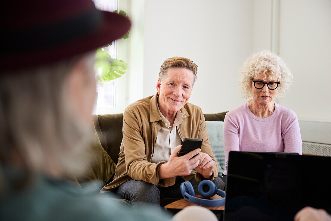 Smiling senior man and woman sitting in living room and using laptop