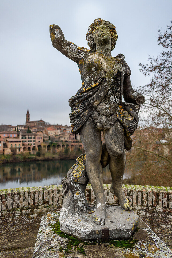 A statue of a goddess on a terrace overlooking the river Tarn to the city skyline of Albi. 