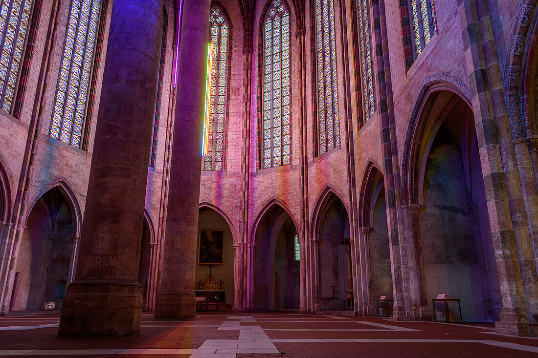 Das Kirchenschiff der Jakobinerkirche, eine Kirche aus dem 13. Jahrhundert, nachts beleuchtet, mit hohen Säulen mit farbigen Lichtern