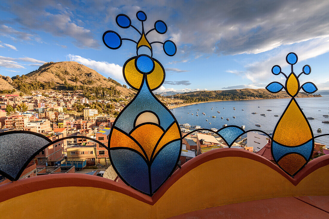 The view over the town of Copacabana and coastline from the hillside, coloured glass shapes on the balcony of a hotel. 