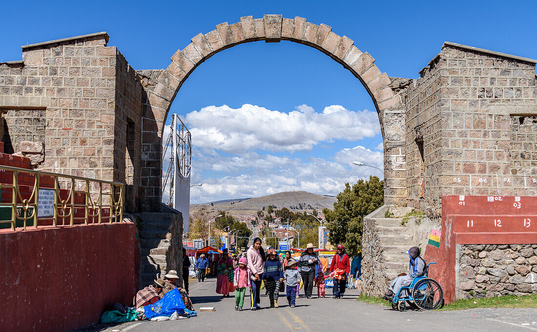 People walking under an arch, across the Peru Bolivia border from Puno in Peru to Copacabana in Bolivia.
